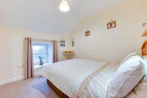 een witte slaapkamer met een bed en een raam bij 3 Bed in Swansea Valley oc-80031 in Pontardawe