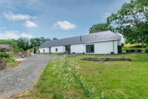 een witte schuur met een grasveld ervoor bij 4 Bed in Drewsteignton oc-bc2408 in Drewsteignton
