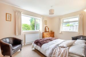 a bedroom with a bed and a chair and two windows at 2 Bed in Dulverton oc-badger in Dulverton