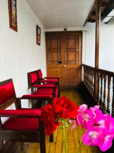 Cuatro sillas y una mesa con flores rojas en una habitación. en Hotel el Conquistador, en Cusco