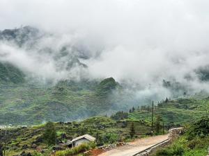 a misty mountain with a dirt road in the foreground at Thào Gia Homestay Mèo Vạc in Ha Giang