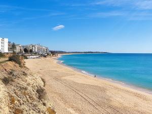 a beach with a person walking on the sand at 11A Rocha - Casas & Papeis in Armação de Pêra