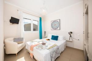 a white bedroom with a bed and a chair at Villa Sequoia Yellow in Barbati