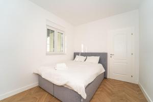 una camera da letto bianca con un grande letto con lenzuola bianche di Villa Oasis Aria a Mostar