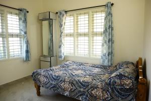 a bedroom with a bed and two windows at Raghavendra Homestay in Kalyānpur