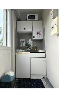 a small kitchen with white cabinets and a sink at Central Studio - Proche Bâle & St Louis in Saint-Louis