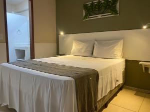 un lit avec des draps blancs et des oreillers dans une chambre dans l'établissement Residencial Lúpulos, à Angra dos Reis 17 autres photos