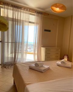 a bedroom with two towels on a bed with a window at Fole Maison in Durrës