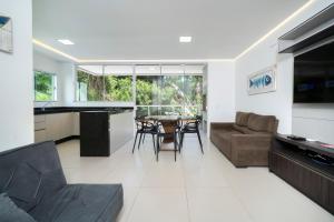 uma cozinha e sala de estar com mesa e cadeiras em Seu Paraíso em Bombinhas Apto Totalmente Equipado a 3 Minutos da Areia em Bombinhas