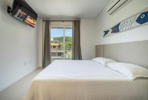 um quarto com uma cama grande e uma janela em Seu Paraíso em Bombinhas Apto Totalmente Equipado a 3 Minutos da Areia em Bombinhas