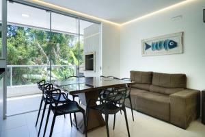 uma sala de estar com uma mesa, cadeiras e um sofá em Seu Paraíso em Bombinhas Apto Totalmente Equipado a 3 Minutos da Areia em Bombinhas