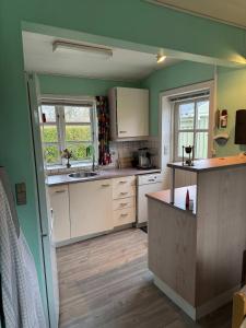 een keuken met groene muren en witte kasten bij Summerhouse in Liseleje in Liseleje