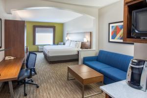 a hotel room with a bed and a blue couch at Holiday Inn Express & Suites Texarkana by IHG in Texarkana