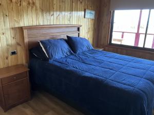 a bedroom with a blue bed and a window at Chiloé,Curaco de Velez casa de veraneo in Curaco de Velez +30 photos