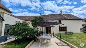a patio with an umbrella and a table and chairs at Ô Coeur des Liens in Saint-Seine-lʼAbbaye