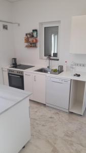 a white kitchen with a sink and a stove at Finikounda in Finikounta +6 photos