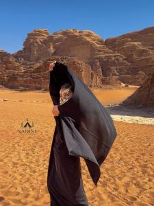 een man die in de woestijn staat met een paraplu bij Nadine Luxury Camp in Wadi Rum