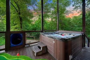 a hot tub on a deck with a large window at 5 Bedroom - Four En-Suite & Bunk Loft w/half bath in Stephens Gap