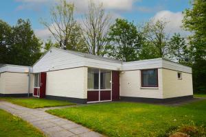 ein kleines weißes Haus mit roten Türen im Hof in der Unterkunft Bungalow 21 - Nelderhut in Simpelveld + 5 Fotos