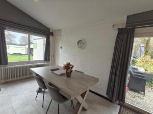 ein Esszimmer mit einem Holztisch und einem großen Fenster in der Unterkunft Bungalow 21 - Nelderhut in Simpelveld