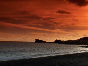 a person walking on the beach at sunset at Aparthotel Barracuda in Ponta Delgada