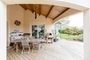 eine offene Terrasse mit einem Holztisch und Stühlen in der Unterkunft Chambre d'hôtes - Acrifolia in Aigrefeuille-sur-Maine