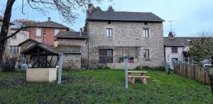 ein altes Steinhaus mit einem Picknicktisch davor in der Unterkunft La forge in Saint-Julien-le-Petit