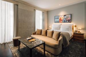 ein Hotelzimmer mit einem Bett, einer Couch und einem Tisch in der Unterkunft MYTHIC SANA Downtown Suites in Lissabon