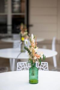 a green vase with flowers sitting on a table at Hotel Jean Moët in Épernay +51 photos