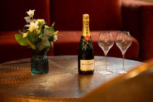 a bottle of wine and two wine glasses on a table at Hotel Jean Moët in Épernay