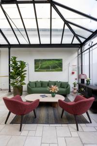 a living room with a green couch and two red chairs at Hotel Jean Moët in Épernay