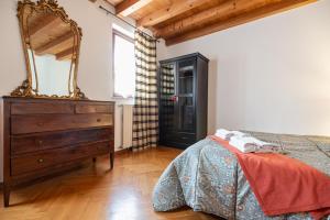 a bedroom with a bed and a dresser and a mirror at Torre Cà Emo, Il Bilocale "Leone di San Marco" in Vittorio Veneto