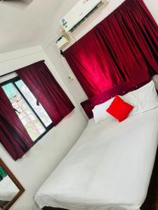 a bedroom with red curtains and a white bed with red pillows at Marlin Beachway Rooms- Baga Beach in Baga +31 photos