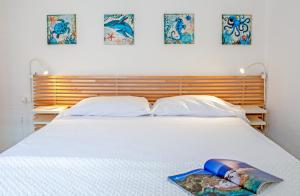 une chambre avec un lit blanc et trois tableaux au mur dans l'établissement Elbamar Lacona, à Lacona