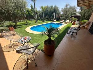 a patio with chairs and a potted plant next to a pool at Najma Ourika in Ourika