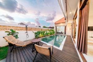 a balcony with a swimming pool and two chairs at Villa Gadang in Kerobokan