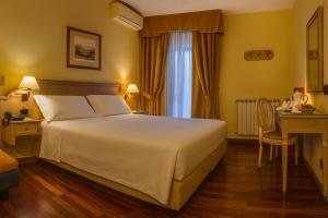 a bedroom with a large white bed and a desk at LVG Hotel Collection - La Bussola in Novara
