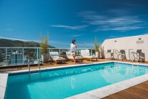 uma mulher em pé no telhado de um prédio ao lado de uma piscina em Angra Beach Hotel em Angra dos Reis