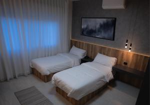 a hotel room with two beds and a tv at Al Jawhara Hotel Suites in Amman