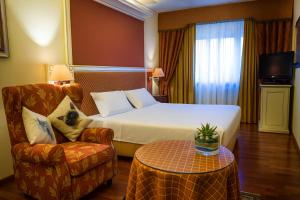a hotel room with a bed and a chair and a table at LVG Hotel Collection - La Bussola in Novara