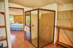 a glass shower in a room with a bed at Manoas in Uvita