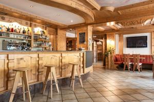 un bar en un restaurante con paredes y taburetes de madera en Wellness Hotel Dolomia, en Soraga