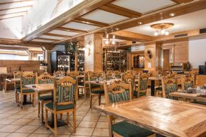 Un comedor con mesas y sillas de madera. en Wellness Hotel Dolomia, en Soraga