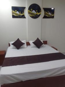 una camera da letto con un letto bianco con tre immagini sul muro di Mayura palace a Jaipur