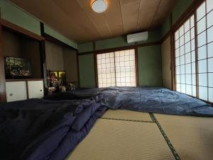 ein großes Bett in einem Zimmer mit zwei Fenstern in der Unterkunft Entire house for rent in Beppu with a dog run in Beppu