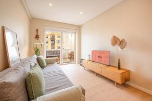 a living room with a couch and a flat screen tv at GuestReady-Charming Coastal Getaway in Almada