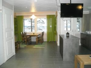 a dining room with a table and green curtains at Aneen Loma Vacation and Cottages in Posio