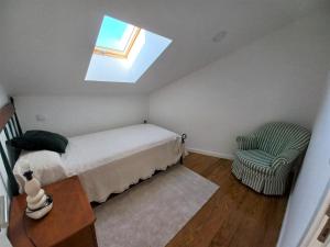 a bedroom with a bed and a chair and a skylight at Ares do mar - Loft and terrace in Matosinhos