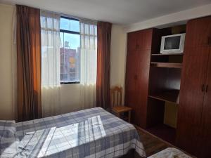 ein Hotelzimmer mit einem Bett und einem Fenster in der Unterkunft Apartamento centrico en Puno in Puno