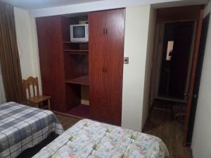 ein Schlafzimmer mit einem Bett und einem Schrank mit einer Mikrowelle in der Unterkunft Apartamento centrico en Puno in Puno + 2 Fotos